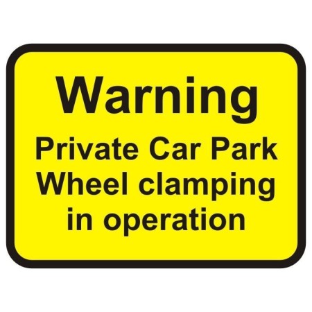 Warning private car park wheel clamping in operation sign with bold black text on yellow background