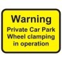Warning private car park wheel clamping in operation sign with bold black text on yellow background